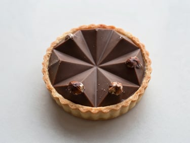 Overhead flat lay of a perfectly sliced geometric chocolate hazelnut tart, revealing clean layers, soft natural light, minimalist composition, elegant editorial photography