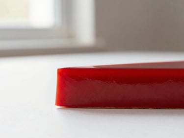 Side profile of a minimalist red fruit entremet, showcasing sharp edges and vibrant red glaze, soft natural light, pristine white background, elegant editorial photography