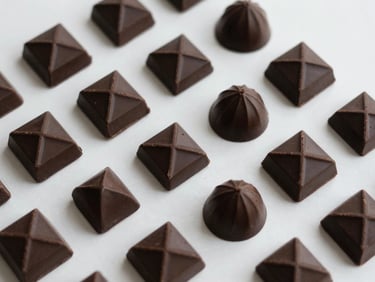 Overhead flat lay of artisanal chocolate bars and geometric bonbons, minimalist composition, soft natural light, deep cacao charcoal tones.