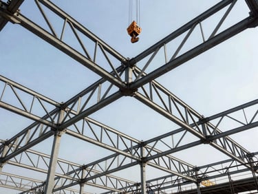 Low-angle perspective of a massive steel truss roof structure under construction, giant crane hook visible against the sky.