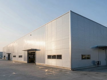 Wide-angle shot of a modern industrial logistics hub with a clean metal facade and insulated sandwich panels, cold morning light.