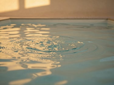 The clean, calm ripple of a heated hydrotherapy pool with warm indirect architectural lighting casting golden reflections