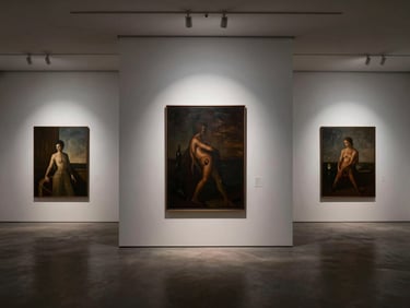 A quiet minimalist gallery interior with large canvas paintings on white walls, soft overhead spotlighting, rich deep shadows, editorial gallery photography