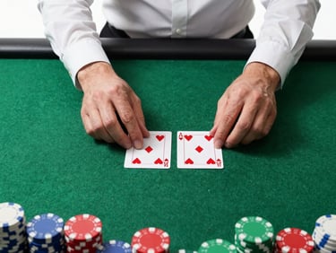 Overhead mid-shot of a blackjack table, dealer's hands mid-deal with two face-up cards, bright high-key studio lighting, dark green felt, chips stacked at frame edge