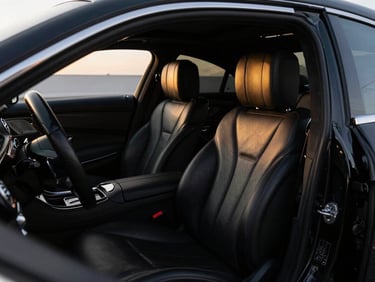Interior shot of a luxurious black Mercedes-Benz S-Class, focusing on the leather seats and spacious cabin, low-key lighting, high-contrast.