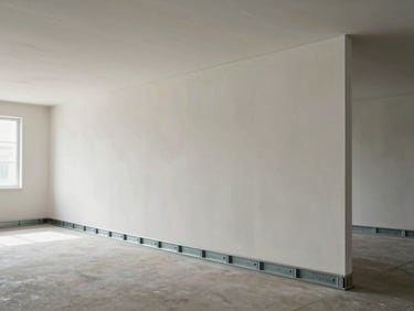 Wide architectural shot of drywall partition system in an empty commercial space, metal track framing visible at base and ceiling, clean seams, diffused daylight from windows at left