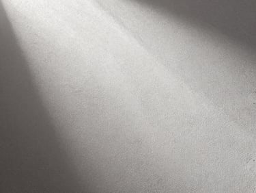 Overhead close-up of raw gypsum plaster surface showing fine uniform texture, controlled studio strobe light raking across the material, no hands, no tools