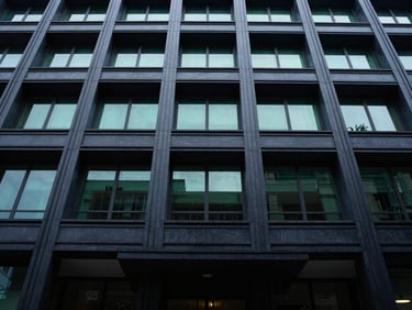 Low-angle photo of a modern courthouse facade, dramatic lighting, sharp architectural lines, deep navy and emerald tones, 35mm