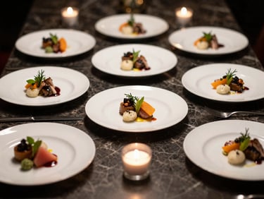 Close-up environmental shot of a private dinner party table set for eight — dark marble surface, individual tasting course plates with precise garnish placement, candlelight supplemented by controlled side lighting, no people visible, emphasis on ingredient texture and plating geometry