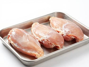 Fresh raw chicken breasts arranged neatly on a stainless steel tray, high-key clean lighting