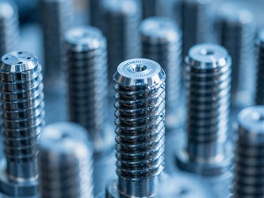 Macro close-up of machined titanium threads, cool blue workshop lighting, sharp focus on tool marks