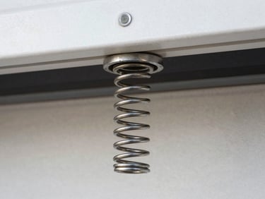 Macro close-up of a high-tension steel torsion spring installed on a garage shaft, clean industrial lighting.