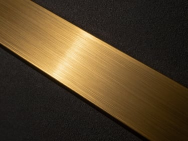 Extreme close-up of a brushed brass inlay transitioning into dark textured plaster, low-key lighting, metallic gold glints, ultra-high resolution