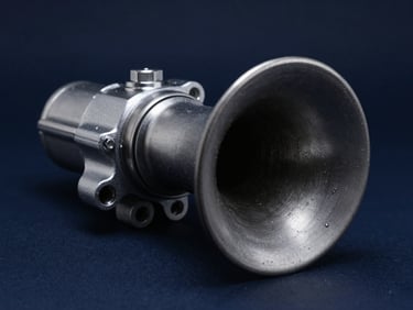 Macro studio shot of a heavy-duty automotive horn, highlighting the rugged metallic housing and precise assembly, cool studio lighting, deep navy tones
