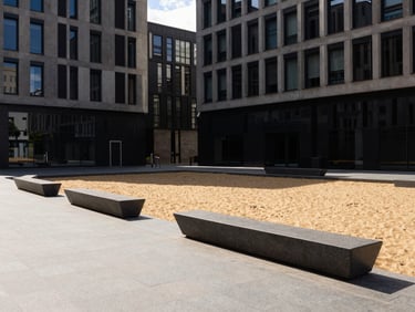 modern architectural photography, sharp natural sunlight, deep shadows, warm sand and charcoal tones, wide-angle lens, 35mm, municipal plaza with clean stone paving and modern public seating