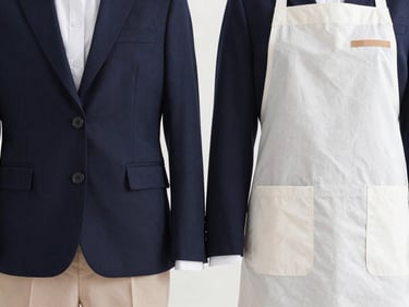 Durable school uniform blazer and specialized hospitality apron side-by-side, clean lines, bright studio light.