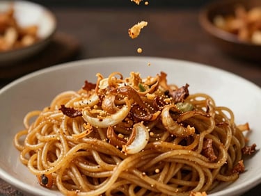 Golden-brown fried shallots being sprinkled onto a hot plate of noodles, showcasing authentic Indonesian food preparation with warm, inviting lighting.