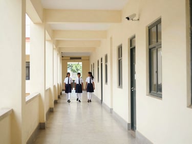Secure school entrance corridor with visible CCTV camera mounted on wall, clean tiled floors, bright and safe atmosphere