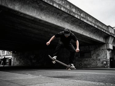 Gritty editorial shot of a skateboarder mid-trick under a concrete overpass in London, moody overcast daylight, high contrast, cool desaturated tones, 35mm film grain.