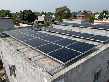 Wide environmental shot of a completed residential rooftop solar installation on a flat concrete home in a Bihar town, overcast daylight, full panel array visible across the rooftop, no people, galvanized mounting rails sharp in the foreground
