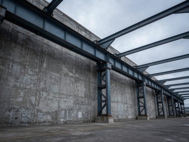 Wide-angle view of a manufacturing floor with concrete walls and steel trusses, dramatic overcast light.