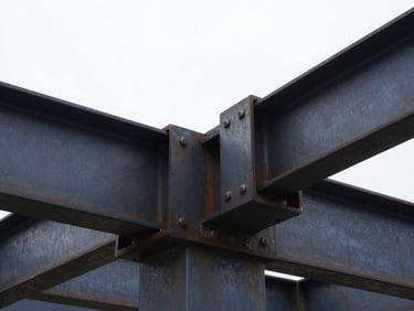 Close-up of industrial steel joints and structural connections, high-contrast overcast daylight, rugged texture.