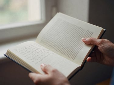 Close-up of hands, one holding a classic psychoanalytic book, the other turning pages of a notebook with handwritten notes, warm natural window light, muted academic tones, shallow depth of field, 35mm film.
