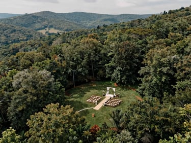 Aerial view of an outdoor wedding ceremony setup in a Tennessee mountain valley, rows of chairs visible from above, overcast soft natural light, no people in frame