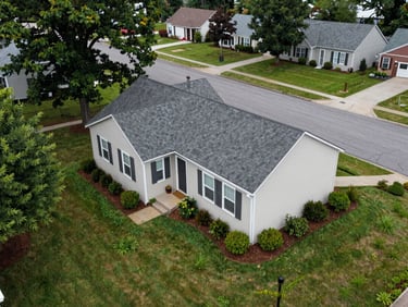 Close overhead aerial of a residential property listing, neat lawn and roofline visible, overcast midday light, East Tennessee neighborhood street below