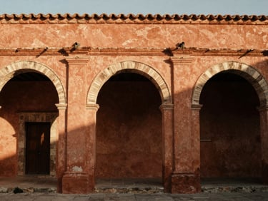 Cinematic architectural detail of a terracotta-walled courtyard in Oaxaca, warm shadows, natural side-lighting