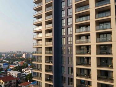 Sunlit high-rise apartment balcony with city views in India, contemporary design, warm natural daylight, deep navy and champagne accents, wide-angle lens