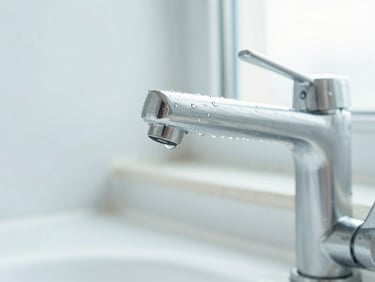 Macro shot of a sparkling clean stainless steel bathroom faucet with water droplets catching bright daylight