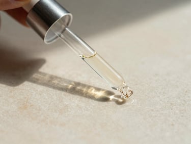 Warm editorial photo of a delicate glass dropper and botanical extracts on an alabaster surface, soft natural light.