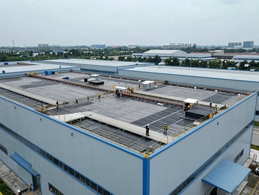 Aerial view of an active industrial building undergoing roof restoration, clean safety protocols, professional engineering
