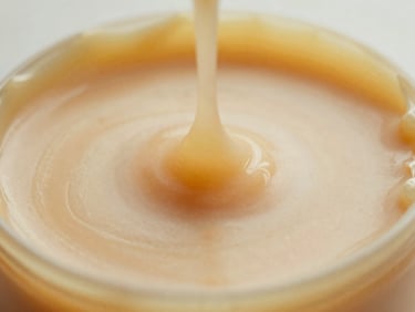 Close-up of premium golden hard wax melting in a warmer, soft diffused daylight, shallow depth of field, 35mm.
