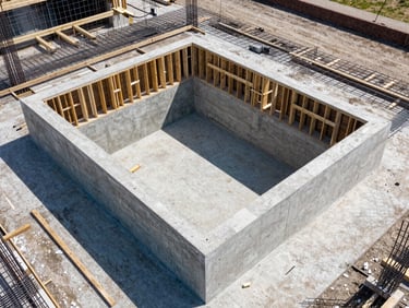 Architectural drone shot of a reinforced concrete pool basin under construction, clean wooden formwork, steel rebar grid, bright daylight
