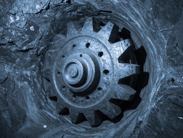 Active tunnel boring machine cutter head in a deep subterranean bore, dramatic shadows, cool ambient blue and gray tones.