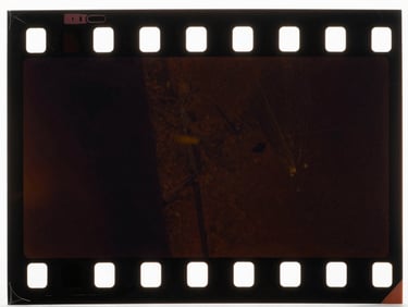 Macro close-up of a damaged 35mm film frame, visible dust, chemical decay, and fading, low-key cinematic lighting, original color degradation