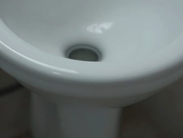 Macro close-up shot of an anti-microbial glazed ceramic urinal rim, showing precise flushing geometry and water outlet, cool studio lighting, sharp focus on glaze texture.
