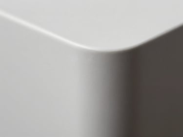 Extreme macro close-up of a perfectly curved solid surface corner joint, flawless white matte texture, dramatic side lighting highlighting the seamless transition.
