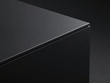 Sleek pure matte black solid surface block, dramatic studio lighting highlighting the perfect seamless curved edge