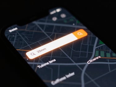 Close-up macro shot of a mobile screen showing a glowing orange local search map interface, dark moody tech aesthetic, 35mm