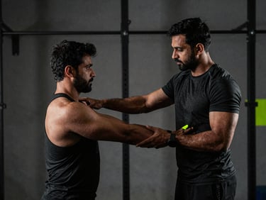 Indian personal coach demonstrating proper form to an athlete in a gym, focus on technique, dramatic lighting, gritty athletic photography