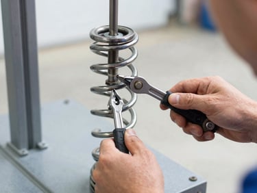 Close-up of a high-tension steel garage door spring being calibrated by a technician's hands using professional tools, bright natural daylight, sharp focus, 35mm.