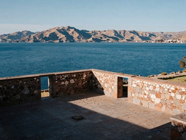 Stone monastery courtyard overlooking the deep blue waters of Lake Titicaca, soft mountain light