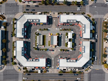 Overhead aerial-style site plan diagram of a commercial plaza, showing 35 numbered retail bays arranged along street frontage, parking lanes and traffic circulation paths clearly visible, natural light overhead perspective, no people, clean documentary framing emphasizing layout geometry
