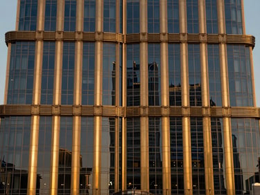 Close-up architectural photography of a premium brass and glass facade in Downtown Dubai, twilight lighting, sharp focus