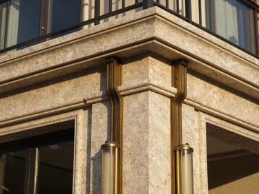 Tight textured detail of premium travertine stone and bronze metalwork on a luxury villa exterior, warm golden hour light
