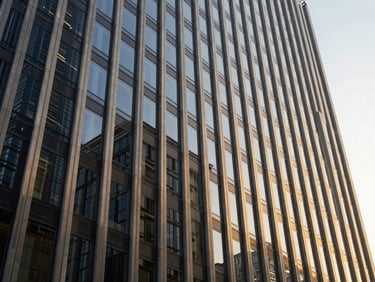 Sleek modern glass and steel corporate skyscraper facade reflecting natural daylight, deep navy and warm gold tones, 35mm