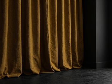 Heavy textured linen curtains catching low-angle side light in a moody architectural space